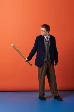 Genç adam, kendine güveni olan tahta bir sopayı tutarken gençlik kültürü ve tarzının bir karışımını sergiliyor..