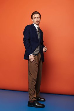 Genç ve yakışıklı bir adam kendine güvenerek şık giyiniyor, çağdaş gençlik kültürünü somutlaştırıyor..