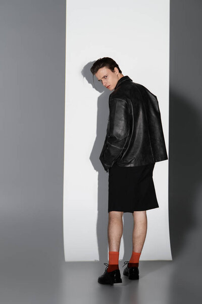 A young handsome man poses confidently in a contemporary outfit, embodying youth culture.