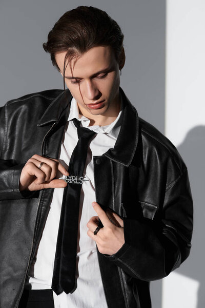 Молодой красивый мужчина в стильной одежде уверенно демонстрирует свой выбор моды