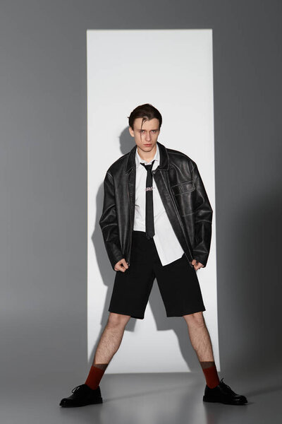 A young man displays his unique style in a bold outfit, exuding confidence in a contemporary space.