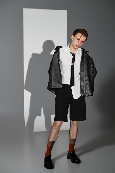 Young man dressed in trendy outfit stands confidently in a minimalist environment.