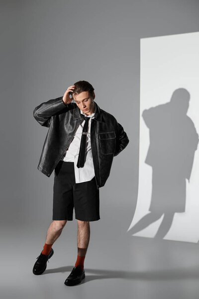 A young handsome man demonstrates unique style in a studio setting with dramatic lighting.