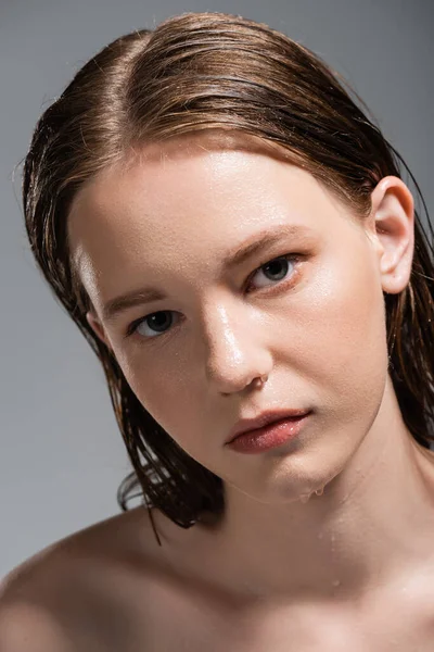 Porträt einer jungen Frau mit nassen Haaren und nasser Haut, die isoliert auf grau in die Kamera blickt — Stockfoto