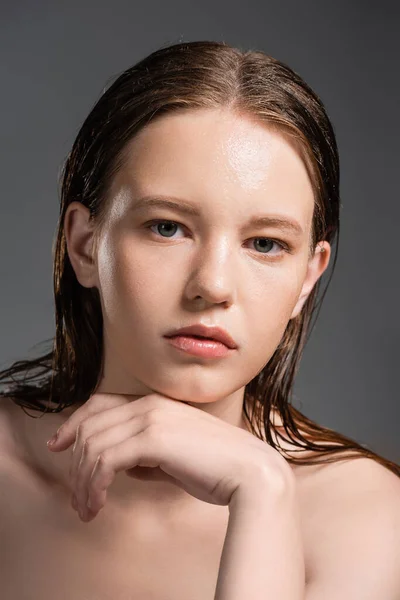 Молода жінка з мокрою шкірою і голими плечима ізольована на сірому — стокове фото