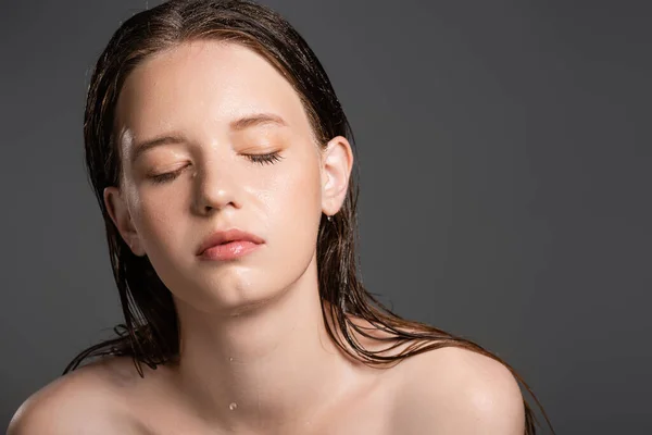 Красива жінка з мокрою шкірою закриває очі ізольовані на сірому — стокове фото