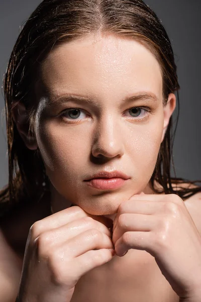Retrato de una bonita joven con la piel mojada tocando la barbilla aislada en gris - foto de stock