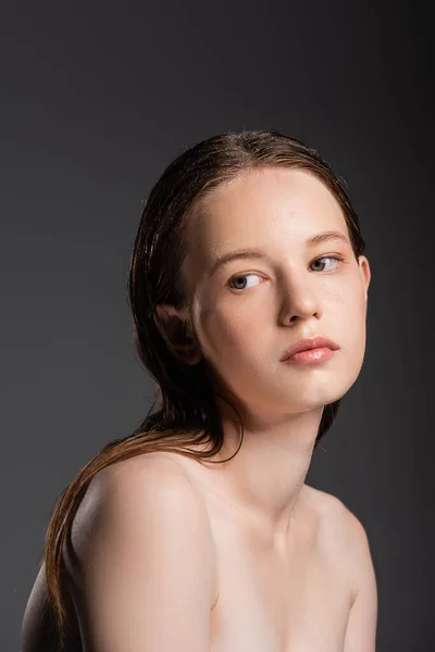 Junge Frau mit nassen Haaren und nackten Schultern schaut vereinzelt auf grau — Stockfoto