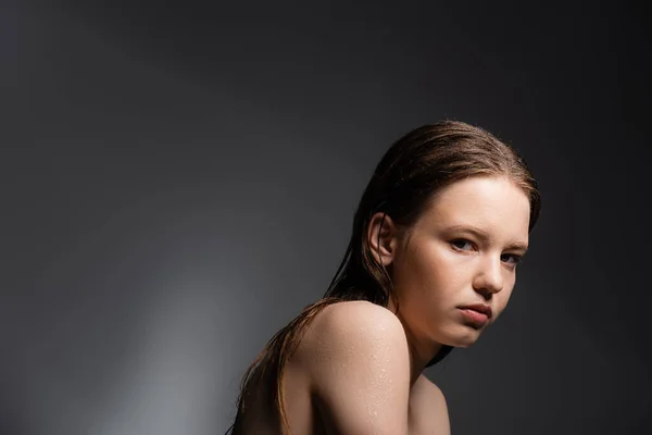 Schönhaariges Model mit nassen Schultern, das in die Kamera auf grauem Hintergrund blickt — Stockfoto