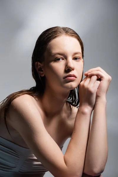 Молода модель з мокрим волоссям позує на сірому фоні — стокове фото