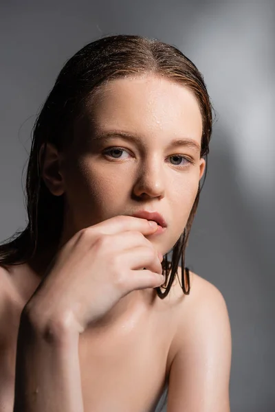 Porträt einer Frau mit nassen Haaren und Haut, die Lippen auf grauem Hintergrund berührt — Stockfoto