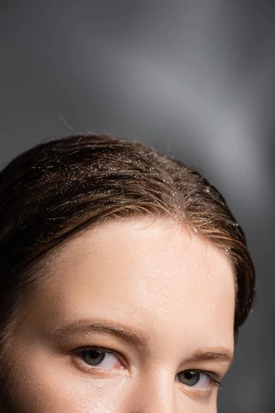 Ausgeschnittene Ansicht einer Frau mit Wassertropfen auf den Haaren, die in die Kamera auf grauem Hintergrund blickt — Stockfoto
