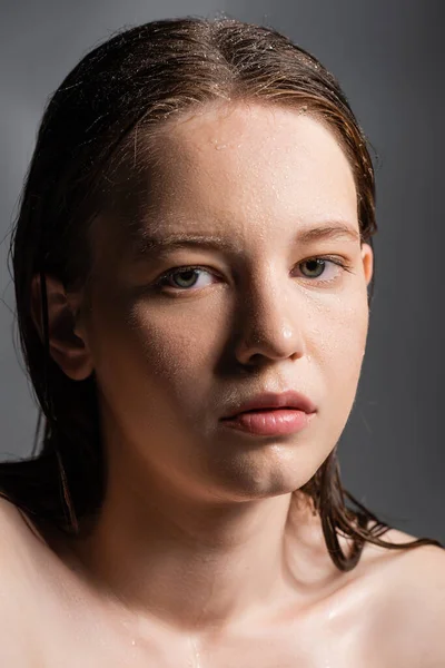 Schönhaariges Model mit nackten Schultern und nasser Haut, das isoliert auf grau in die Kamera blickt — Stockfoto