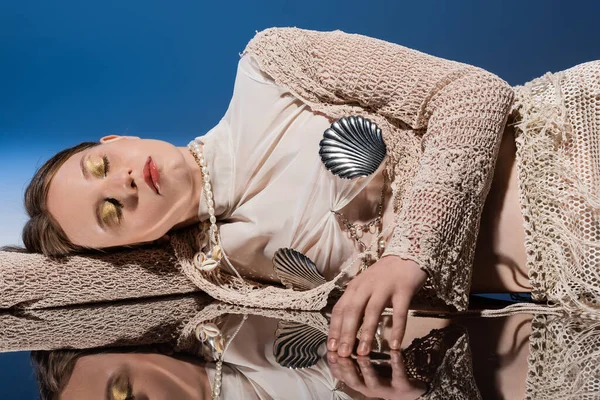 Jolie sirène en jupe résille et cardigan tricoté couché sur miroir sur fond bleu dégradé — Photo de stock