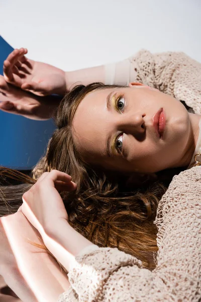 Model in knitted cardigan lying on mirror on grey background — Stock Photo