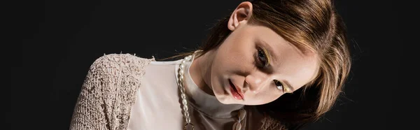 Junge Frau mit Make-up und Perlenkette blickt vereinzelt in die Kamera auf schwarz, Banner — Stockfoto
