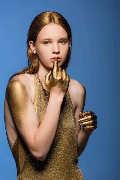 Modelo de pelo limpio con pintura dorada en las manos tocando los labios aislados en azul - foto de stock