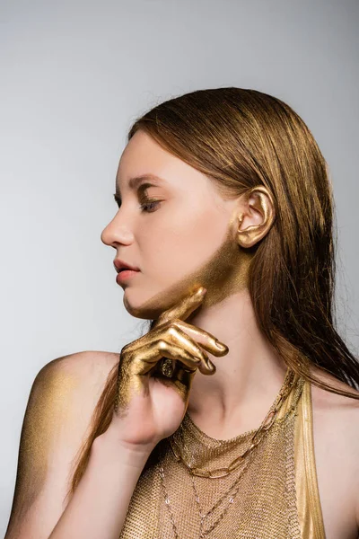 Hübsches junges Model mit goldener Farbe an der Hand und Kinn posiert isoliert auf grau — Stockfoto