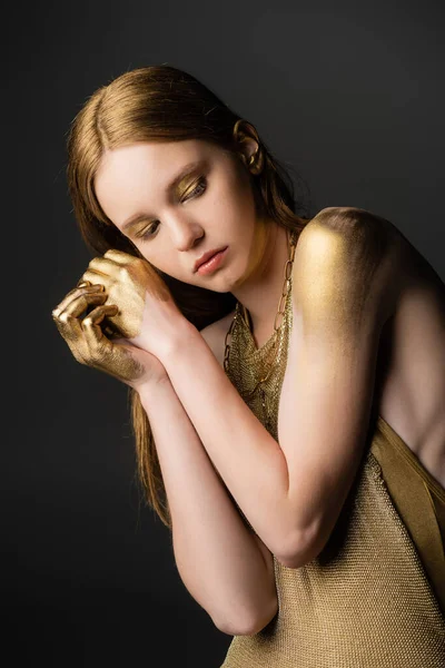 Young woman in golden paint and dress posing isolated on grey — Stock Photo