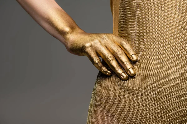 Vue recadrée de la femme en robe dorée et peinture brillante à la main isolée sur gris — Photo de stock