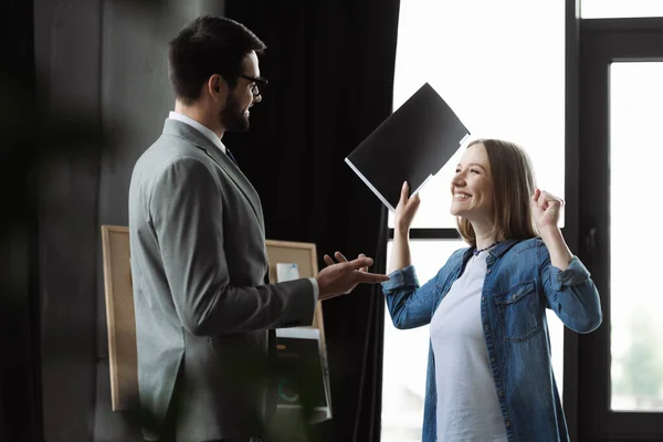 Щаслива жінка тримає резюме в паперовій теці біля менеджера в офісі — стокове фото