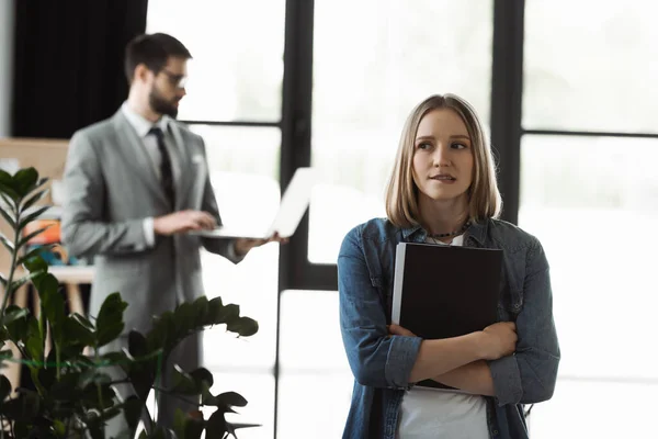 Femme nerveuse tenant un CV près d'un homme d'affaires flou au bureau — Photo de stock