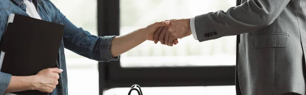 Cropped view of woman with resume shaking hand of businessman in suit in office, banner — Stock Photo