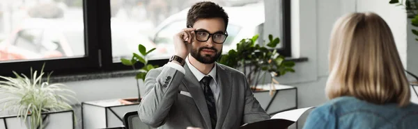 Бізнесмен у костюмі та окулярах тримає резюме біля розмитого кандидата в офісі, банер — стокове фото