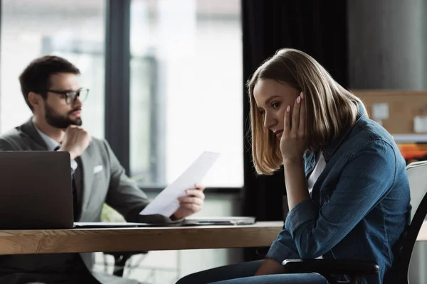 Donna preoccupata seduta vicino a un uomo d'affari offuscato con curriculum sul colloquio di lavoro — Foto stock