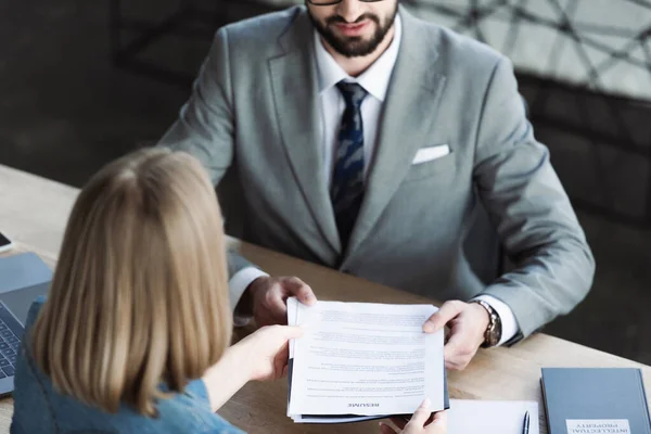 Young woman giving resume to businessman on job interview — Stock Photo
