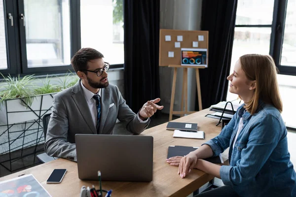 Empresário apontando para candidato a emprego perto de dispositivos durante entrevista de emprego no escritório — Fotografia de Stock