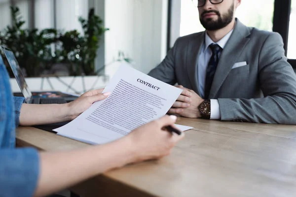 Cropped view of candidate holding contract near blurred manager during job interview — Stock Photo