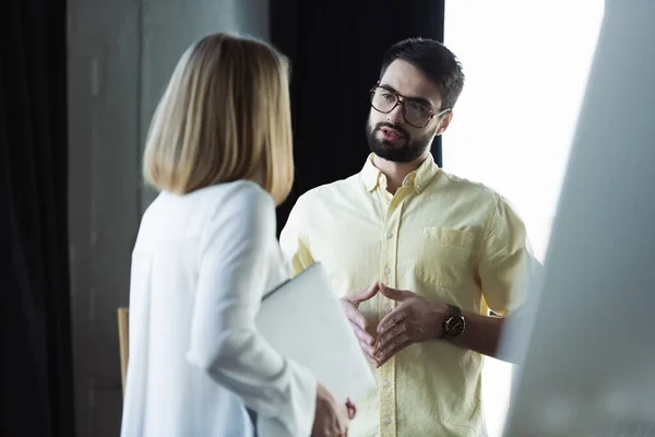 Manager in eyeglasses talking to blurred worker with laptop during internship in office — Stock Photo