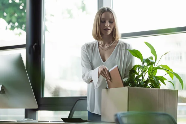 Nuovo lavoratore che prende la cartella di carta dalla scatola vicino al computer portatile in ufficio — Foto stock