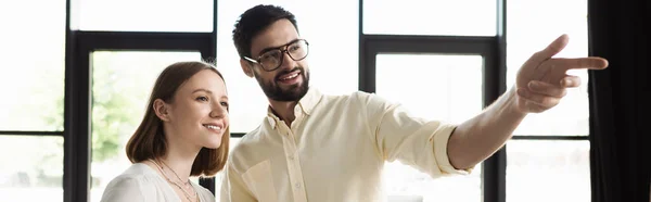 Веселый бизнесмен, указывающий пальцем на стажера в офисе, баннер — стоковое фото
