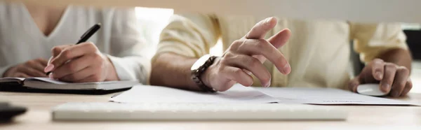 Cropped view of businessman pointing near intern writing on notebook in office, banner — Stock Photo