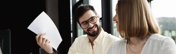 Улыбающийся менеджер в очках держит бумагу рядом с новым работником в офисе, баннер — стоковое фото