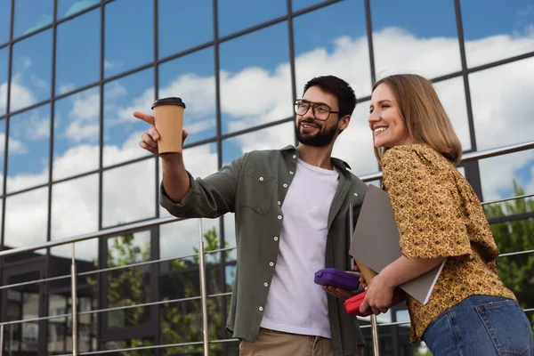 Smiling business people with lunch boxes and coffee to go looking away on urban street — Stock Photo