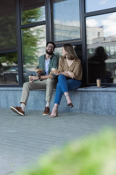 Gente alegre de negocios hablando mientras almuerza con café al aire libre — Stock Photo
