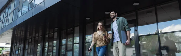 Gente d'affari sorridente con gadget e caffè che cammina per strada urbana, striscione — Foto stock