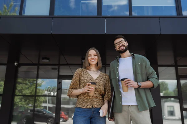 Jóvenes empresarios con café para llevar y dispositivos mirando a la cámara al aire libre - foto de stock