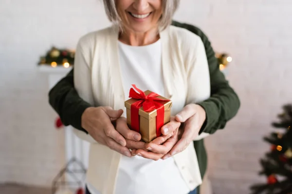 Vista ritagliata di uomo maturo e donna felice che tiene il Natale presente nelle mani — Foto stock