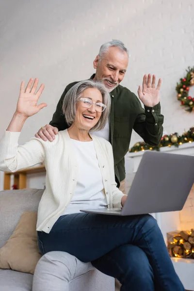 Happy middle aged husband and wife waving hands during video call on christmas holidays — Stock Photo