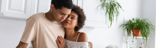 Heureux et sexy afro-américaine femme étreignant jeune petit ami dans la cuisine, bannière — Photo de stock