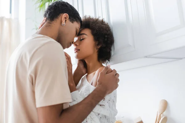 Jeune couple afro-américain debout face à face avec les yeux fermés dans la cuisine — Photo de stock