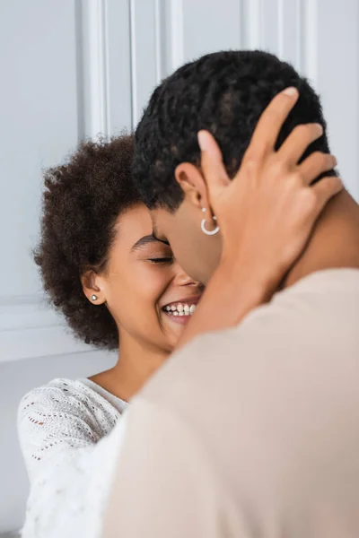 Alegre afro-americana mulher abraçando cabeça de jovem namorado na cozinha — Fotografia de Stock