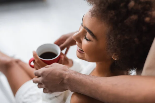 Высокий угол зрения мужчины, держащего чашку кофе рядом с африканской женщиной — стоковое фото