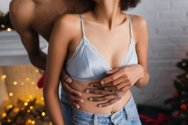 Cropped view of african american woman in bra near boyfriend embracing her on christmas eve — Stock Photo