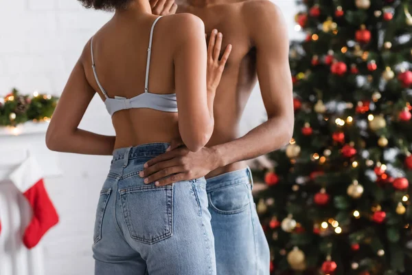Vue partielle de femme américaine africaine sexy en jeans et soutien-gorge près de jeune copain torse nu — Photo de stock