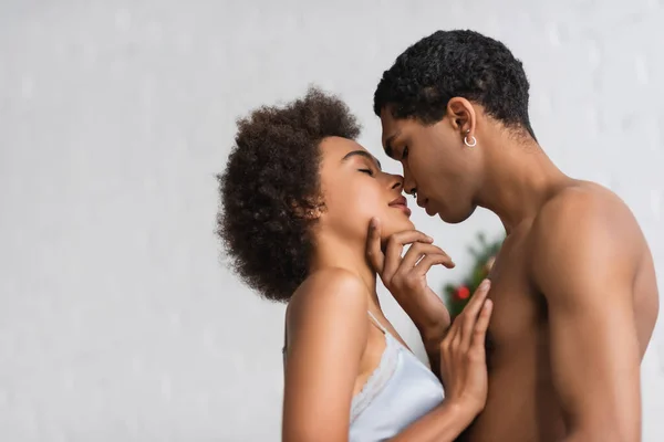 Vista lateral do homem americano africano sem camisa tocando rosto de namorada sexy no sutiã — Fotografia de Stock